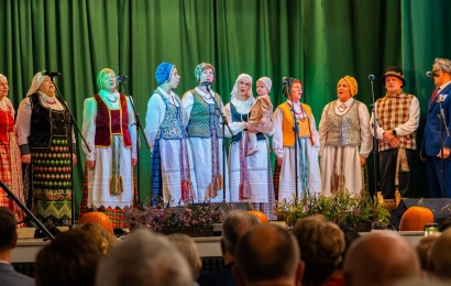 Tautiniais drabužiais vilkintys šventės dalyviai dainuoja Luksnėnų scenoje.