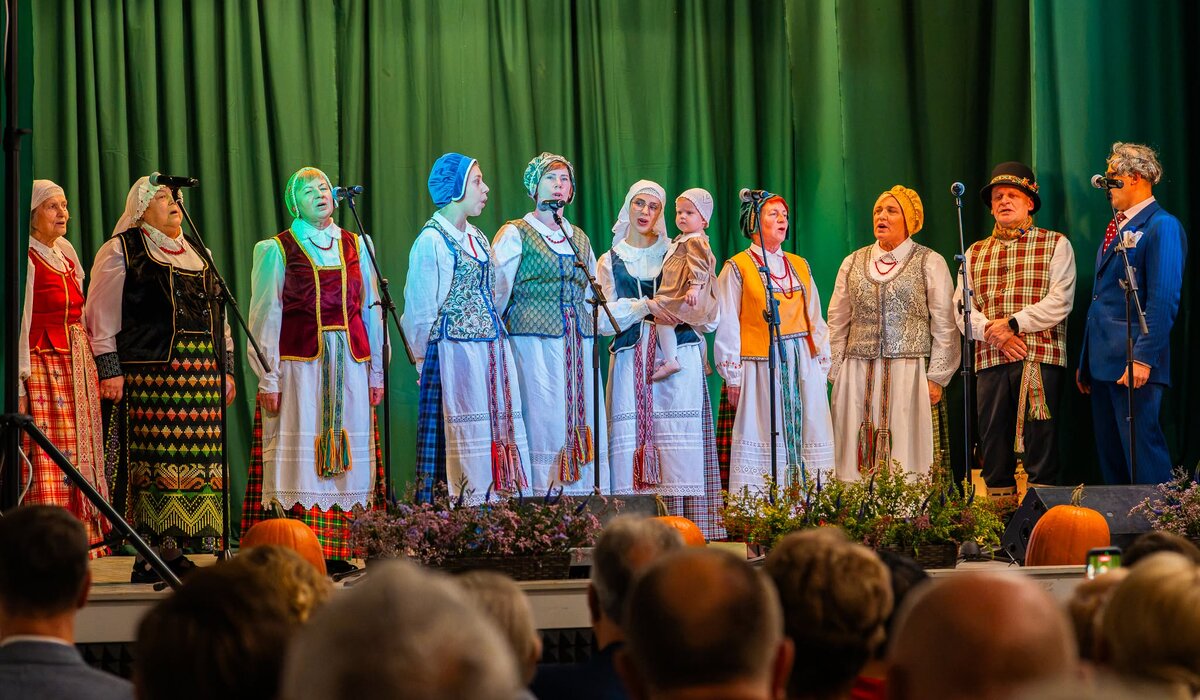 Tautiniais drabužiais vilkintys šventės dalyviai dainuoja Luksnėnų scenoje.