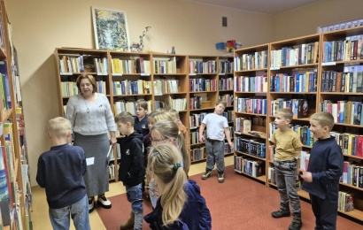 Miroslavo pirmokai su bibliotekininke tarp bibliotekos knygų lentynų.